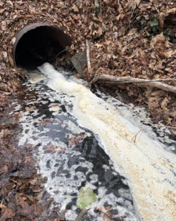 A stormwater outfall with water rushing from the drain pipe.