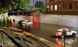 A flooded Merrimack Street in Lawrence, MA is pictured with cars struggling to navigate the high waters. 